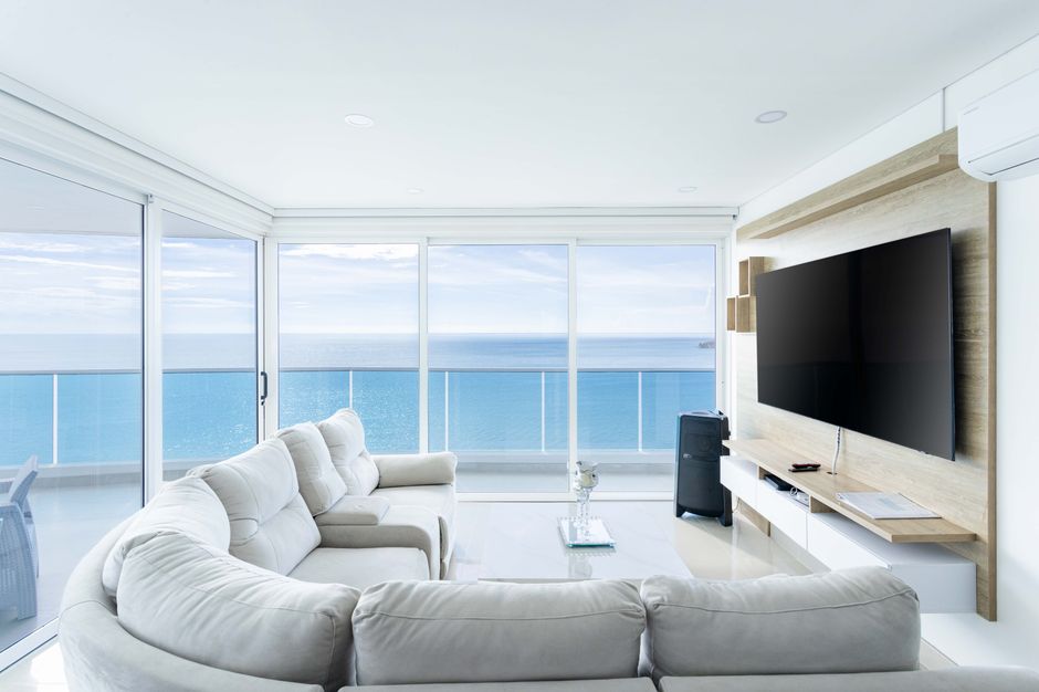 Bright and elegant oceanfront living room with white furniture and a TV in Santa Marta.